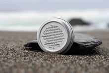 Beard balm tin with ingredients label on a beach